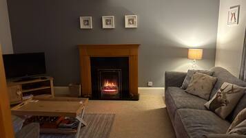 A living room with a fireplace, a television, and a sofa with decorative pillows.