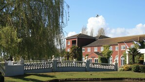 A building with a red facade, a white fence, and a pond in front.