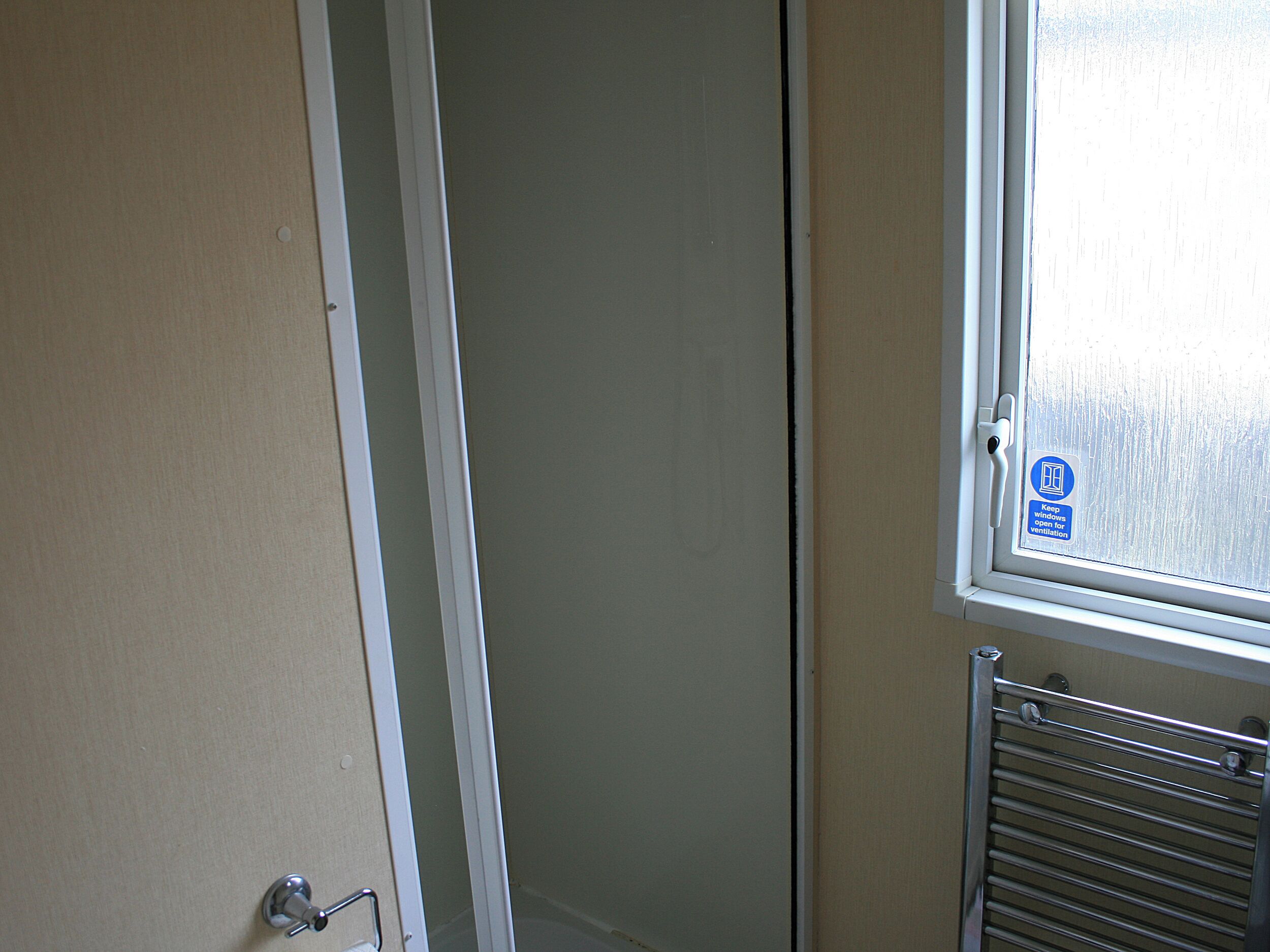A bathroom with a window, a towel rack, and a door.