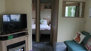A compact room with a television, a bed, a sofa, and a mirror.