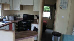 A compact kitchenette with a stove, sink, and storage cabinets.
