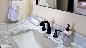 A bathroom with a marble sink, black faucet, and a bottle of soap. - The Windmill Motel (Olney)