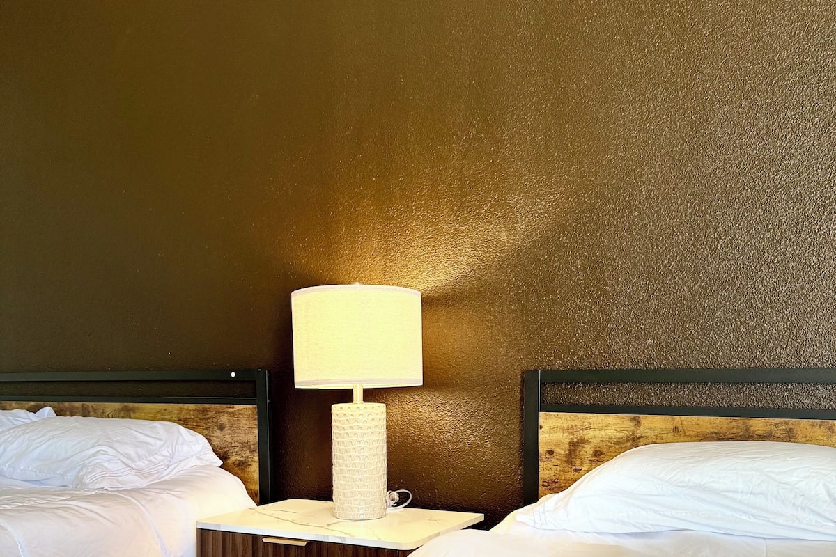Une chambre d’hôtel avec deux lits, une table de chevet avec une lampe et un mur à motifs.