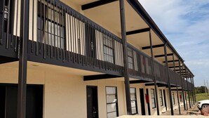 A modern building with a flat roof, large windows, and a balcony with metal railings. - The Windmill Motel (Olney)