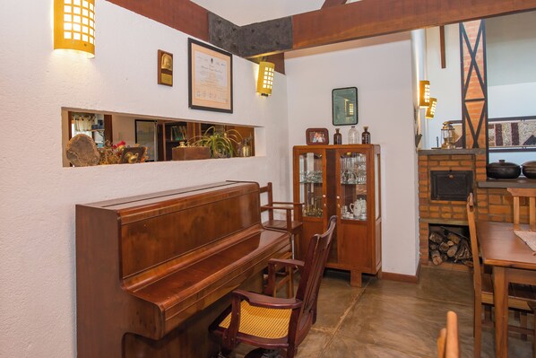 A room with a wooden piano, a cabinet with glass doors, and a fireplace. - Pousada Verbicaro - Santa Maria Madalena (Santa Maria Madalena)