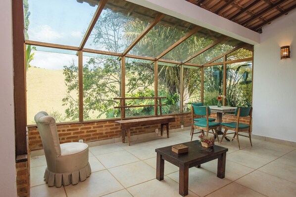 A room with a large glass window, a bench, a table, and two chairs. - Pousada Verbicaro - Santa Maria Madalena (Santa Maria Madalena)