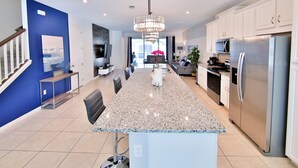 Una cocina moderna con una isla grande, electrodomésticos de acero inoxidable y una araña.