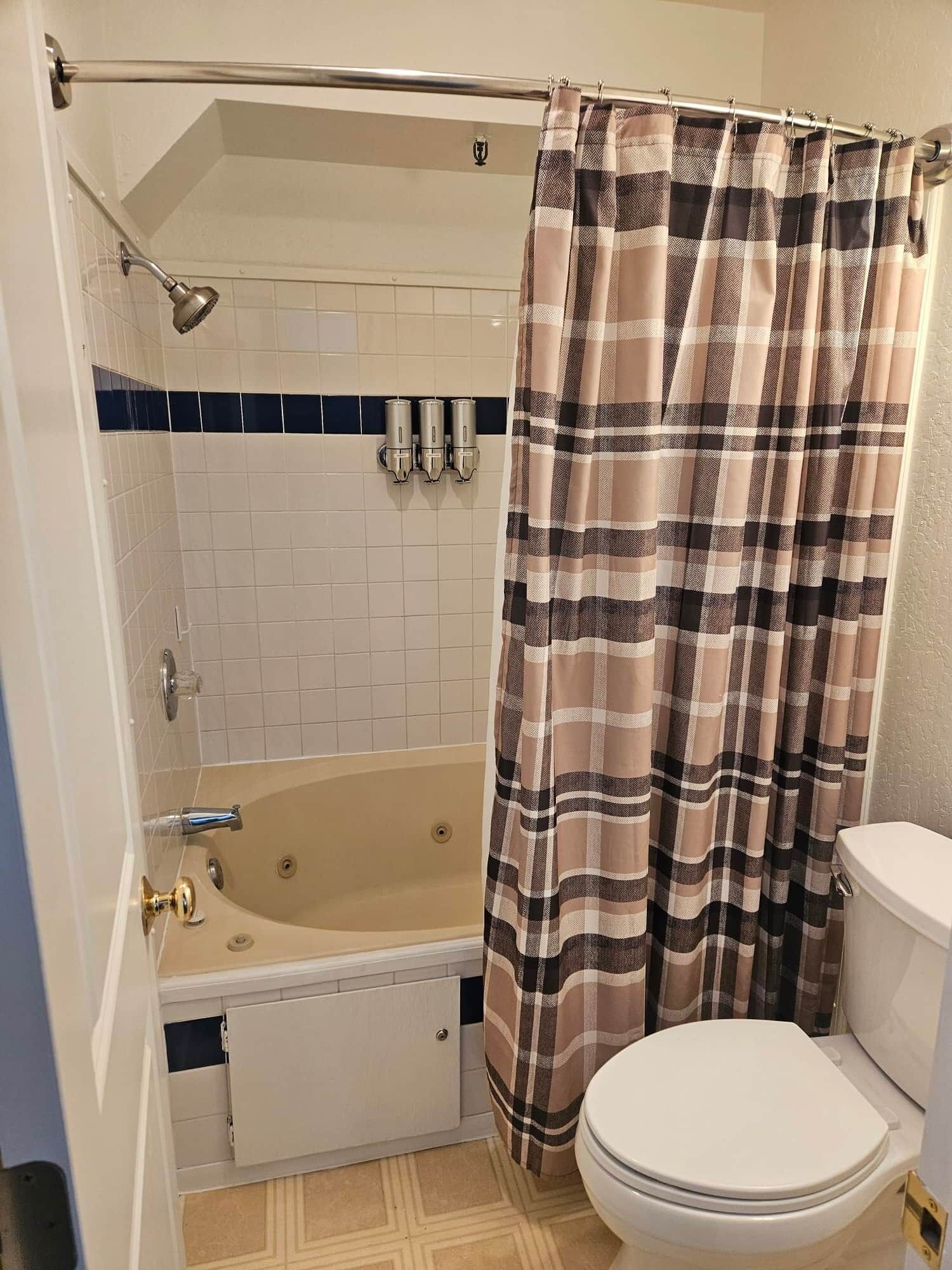 A bathroom with a bathtub, toilet, and a shower curtain.