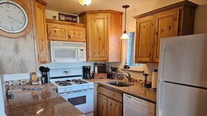 A kitchen with wooden cabinets, a stove, a microwave, a sink, and a refrigerator.