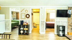 A spacious living area with a flat-screen TV mounted on a brick wall, a wooden coffee table, and a bookshelf with various decorative items. - Winter Ski Trip Getaway (Bessemer)