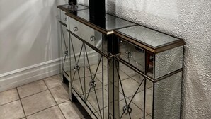 Un baño moderno con tocador de vidrio, un espejo grande y dos plantas de bambú.