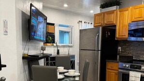 Una cocina moderna con comedor, electrodomésticos de acero inoxidable y un televisor de pantalla plana montado en la pared.