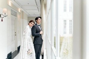 A hallway with a white door, a window, and a view of a building outside. - The Hermitage, a Tribute Portfolio Hotel, Jakarta (Central Jakarta)