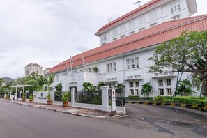 A white building with a red roof, a gated entrance, and potted plants along the sidewalk. - The Hermitage, a Tribute Portfolio Hotel, Jakarta (Central Jakarta)