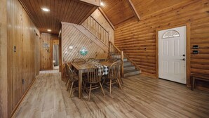 Un interior de madera con una mesa de comedor, sillas, una escalera y una puerta.