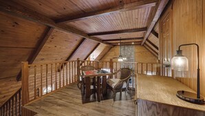 Un interior de madera con zona de comedor, una escalera y un ventilador de techo.