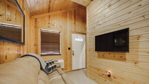 Une pièce chaleureuse avec un canapé beige, un téléviseur à écran plat fixé au mur et un lambris en bois.