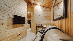 L’intérieur chaleureux d’un chalet avec des murs en bois, un canapé en cuir, un téléviseur et un miroir.