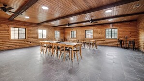 A spacious room with a large wooden table and chairs, multiple windows, and ceiling fans. - Timber Lodge Ranch - The Ranch (Amity)