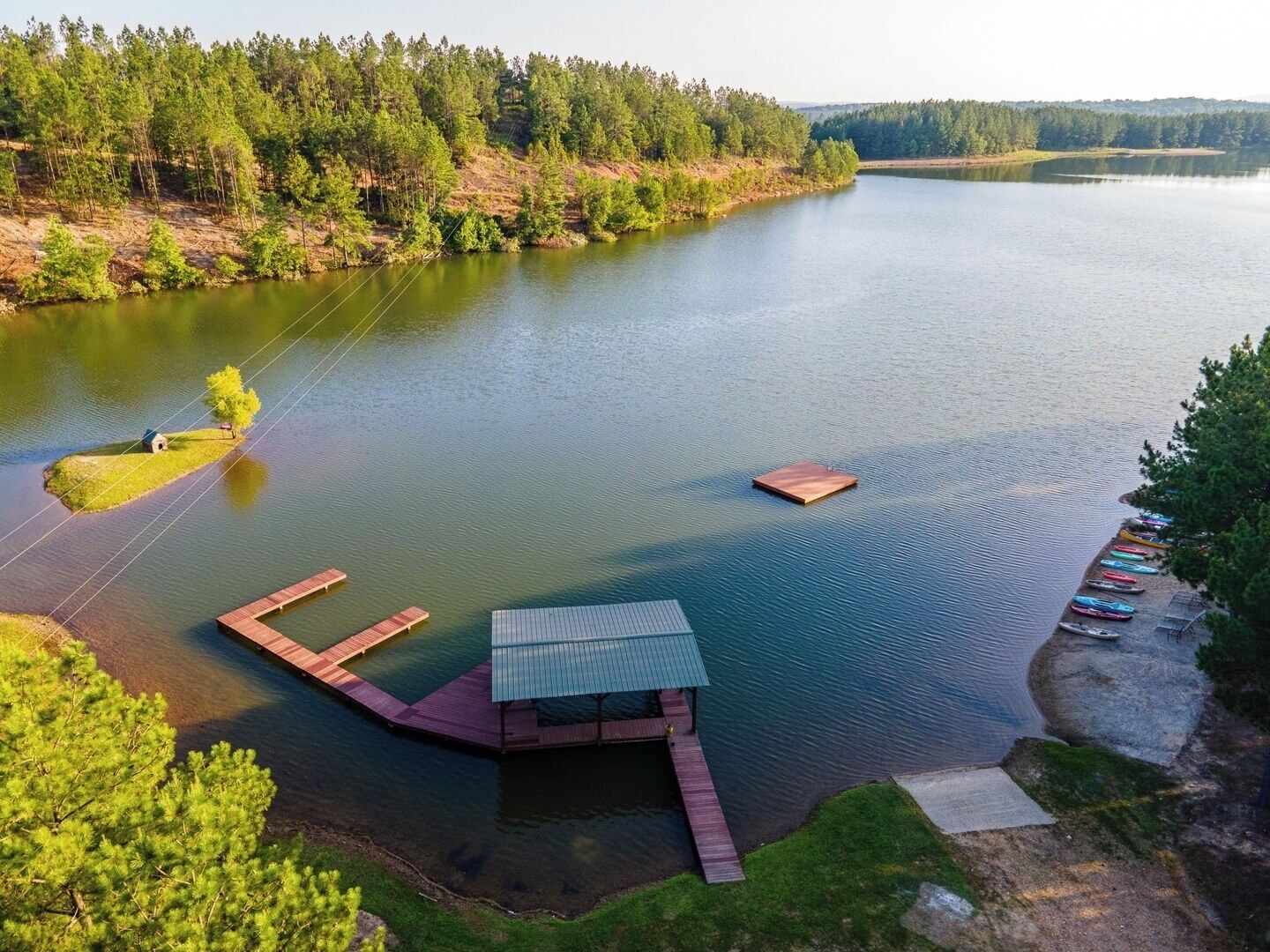 Una propiedad frente al lago con un muelle, una cabaña pequeña y una fila de canoas.