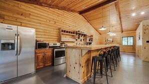 Une cuisine moderne dotée d’appareils électroménagers en acier inoxydable, de meubles de rangement en bois et d’un coin bar avec des tabourets.
