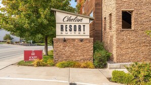 Une enseigne pour le complexe hôtelier Chelan Resort Suites, avec une façade en pierre et un ciel dégagé.