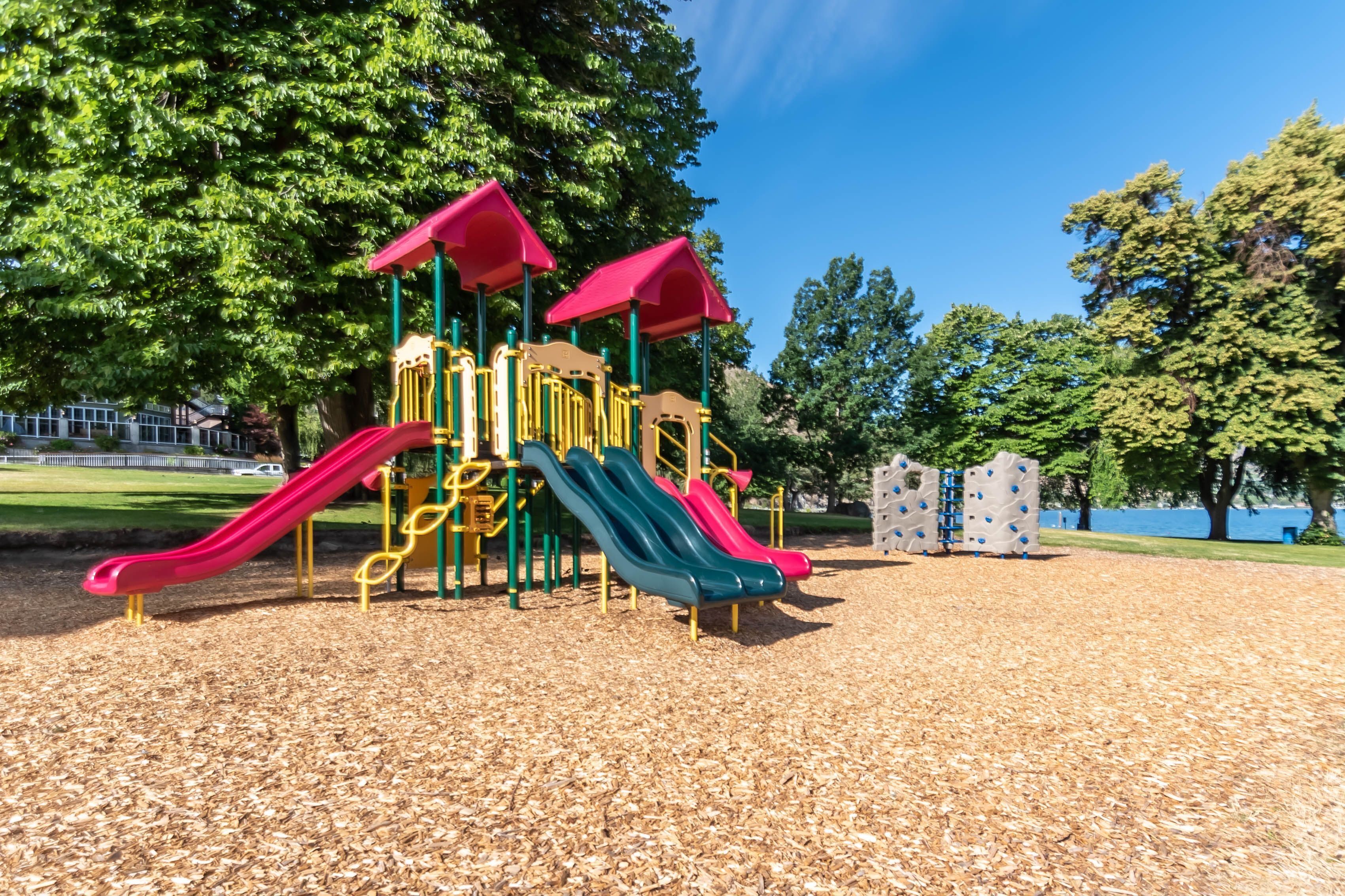 Community playground area with slides, climbing walls, and wood chip ground cover.