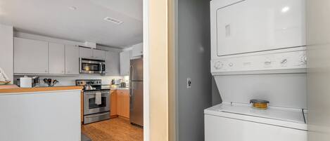 Eine moderne Küche mit weißen Schränken, einem eingebauten Backofen, einer Mikrowelle und einem Edelstahl-Kühlschrank.