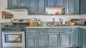Una cocina con armarios azul oscuro, electrodomésticos de acero inoxidable y techo de madera.