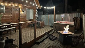 Eine Holzterrasse mit Sitzgelegenheit und Feuerstelle.