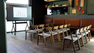 A conference room with a presentation screen, wooden chairs, and a wooden bench.