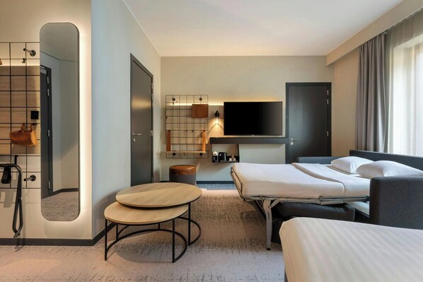 Habitación de hotel con cama, televisión, espejo, mesita y armario.