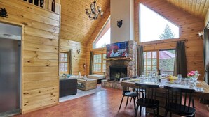 A cozy cabin interior with a fireplace, wooden walls, and a dining area. - Peaceful Rustic Escape, Cool Deck with Firepit Table - No Better Escape than Our Private Lot - 3BR w/Game Loft, Pac Man tabletop games console! (Big Bear)