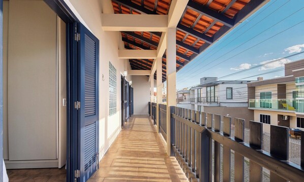 A corridor with a wooden floor, blue shutters, and a view of neighboring buildings. - 5 Bedroom House 200 m From the Beach Cmm0043 (Penha)
