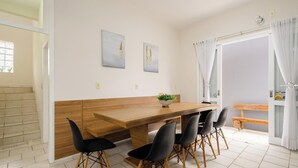 A dining area with a wooden table, black chairs, and two wall-mounted paintings.
