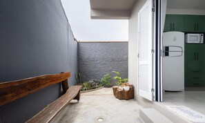 A narrow outdoor space with a wooden bench, potted plants, and a door leading to a kitchen area with a refrigerator and microwave. - 5 Bedroom House 200 m From the Beach Cmm0043 (Penha)