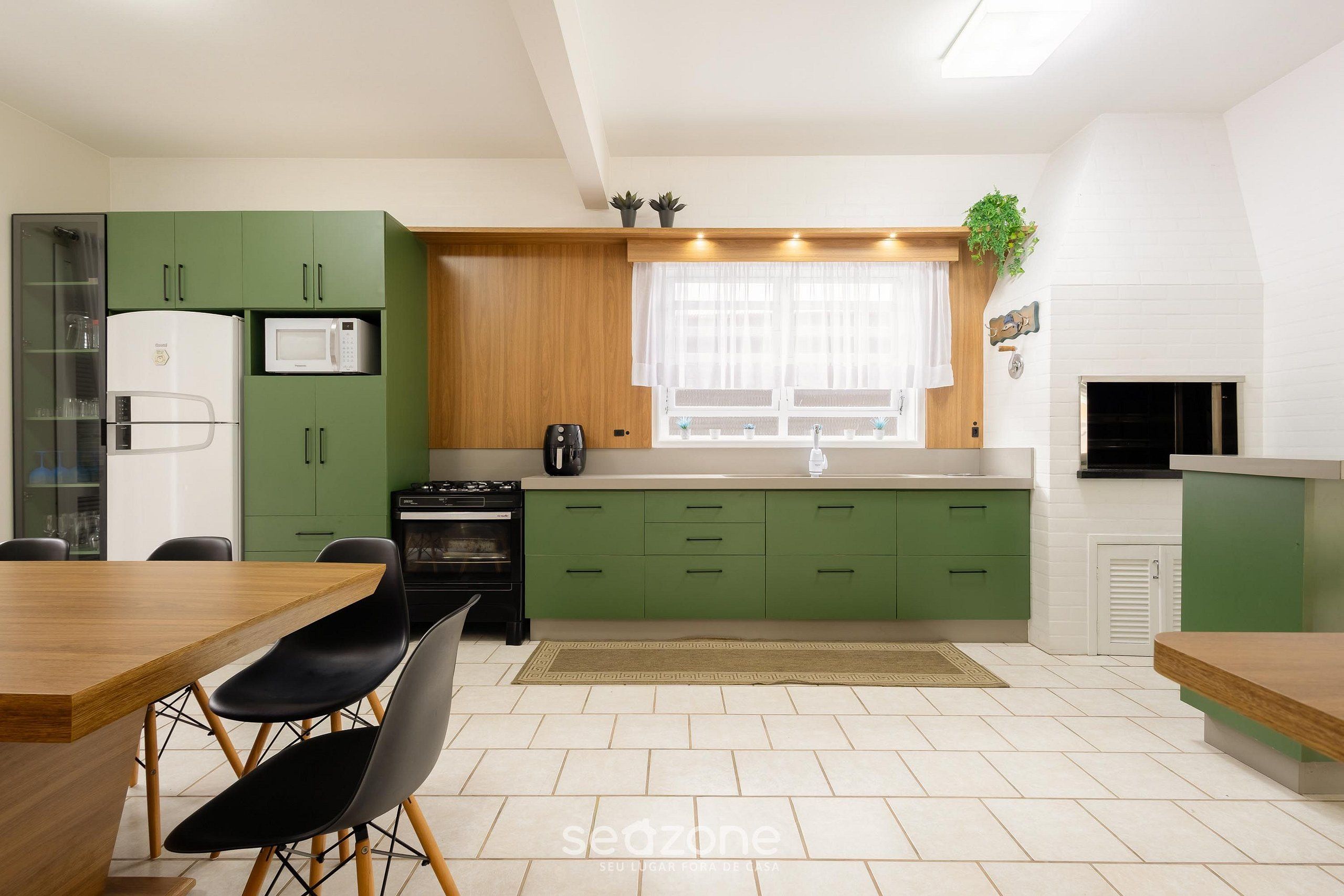 A modern kitchen with green cabinets, a wooden dining table, and a black stove.