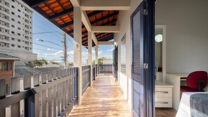 A balcony with a wooden floor, a view of a building, and a red chair.