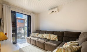 Una sala de estar con un sofá, una lámpara y un ventanal corredizo que da a un espacio exterior.