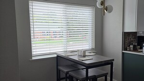 A small dining area with a table and two chairs, a window with blinds, a ceiling light fixture, and a kitchen area with cabinets. - 4-bedroom house in Denver (Denver)