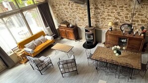 Um quarto aconchegante com parede de pedra, um banco de madeira, uma mesa com cadeiras e uma lareira.