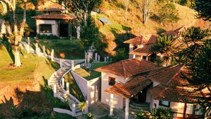 A residential area with multiple houses, a paved driveway, and surrounding greenery. - Atiaia Jungle River Retreat (Bocaina de Minas)