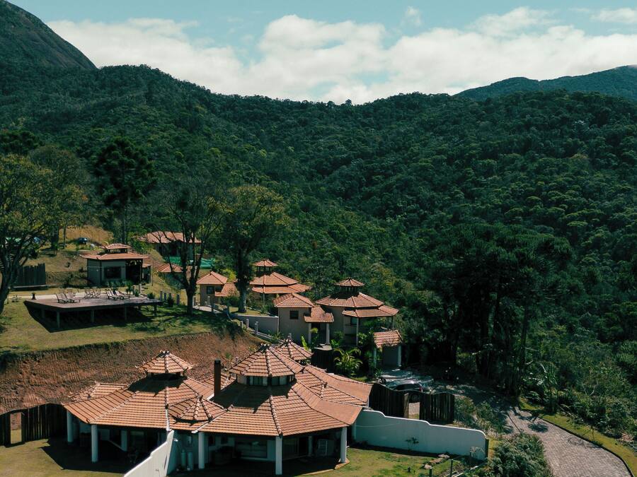 A resort with multiple buildings featuring terracotta roofs, surrounded by lush greenery and hills.