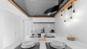 A modern kitchen with white cabinets, a marble backsplash, and a dining area set for two with a table, chairs, and a chandelier. - Luxury mini-chalets to disconnect for two with a private spa nestled in the hear (VAL DES LACS)