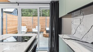 Una cocina moderna con un amplio ventanal, terraza de madera y zona de estar al aire libre.