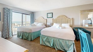 Une chambre d’hôtel avec deux lits, une grande fenêtre et vue sur l’océan.