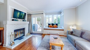 A living room with a fireplace, a television, a sofa, and a window seat. - Chateau Ridge (The Blue Mountains)