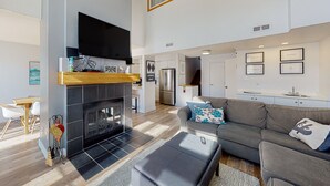 A modern living room with a fireplace, grey sofa, and a flat-screen TV mounted on the wall. - Chateau Ridge (The Blue Mountains)