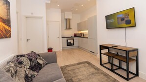 Una sala de estar moderna con un sofá gris, una mesa de centro de madera y un televisor de pantalla plana montado en la pared.