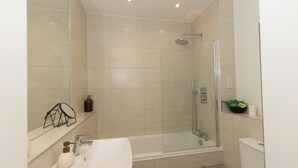 Un baño moderno con ducha de vidrio, lavabo blanco y retrete.